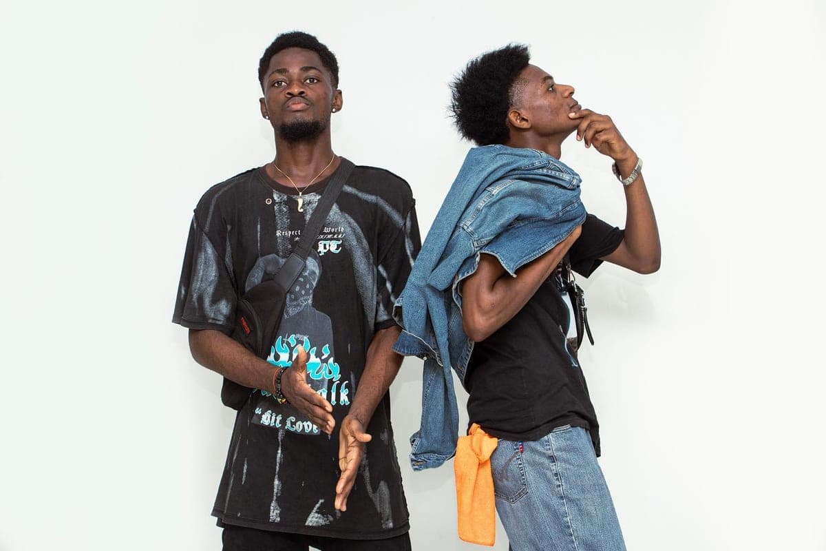 Deux artistes en streetwear devant un fond clair.